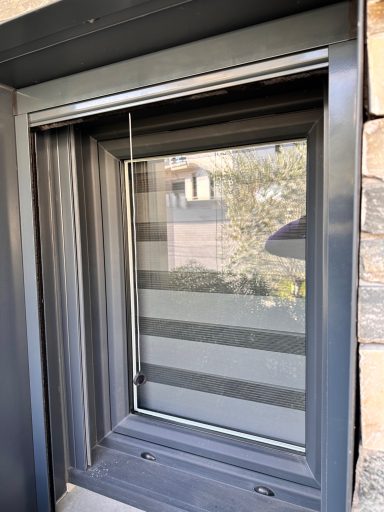 Fenêtre moderne avec des stores horizontaux, vue sur l'extérieur.