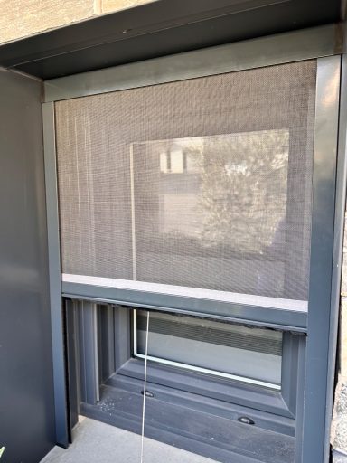 Fenêtre avec moustiquaire intégrée, encadrée de métal gris.
