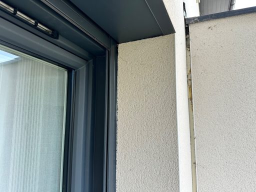 Coin d'un mur avec une fenêtre, montrant un angle et une texture de surface.
